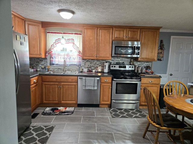 kitchen featuring sink, backsplash, ornamental molding, stainless steel appliances, and a textured ceiling