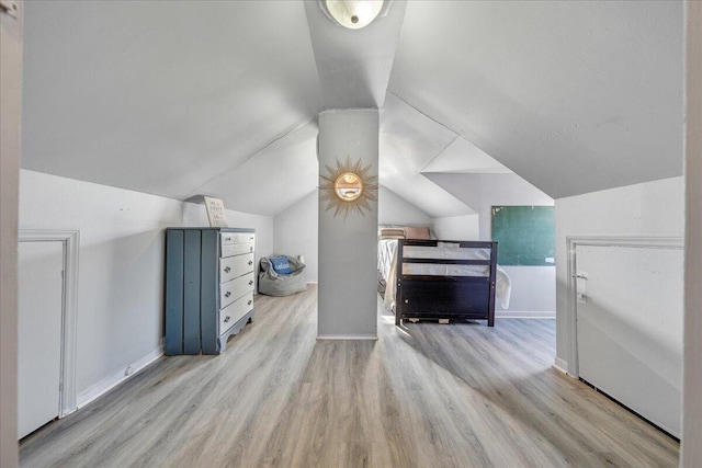 bonus room with light wood-type flooring and vaulted ceiling