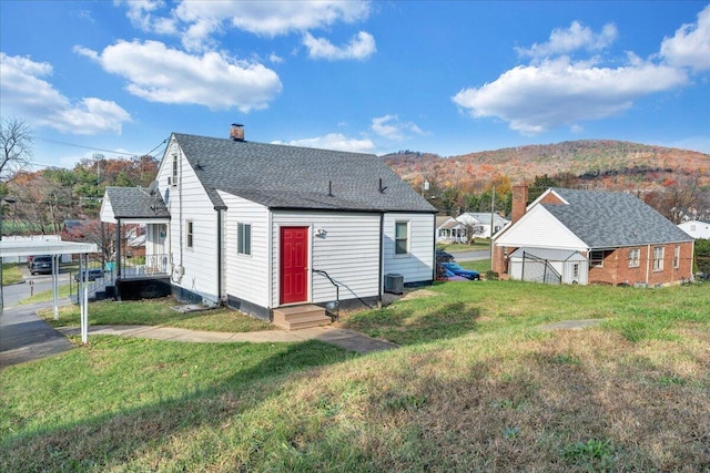 back of house with central air condition unit, a mountain view, and a yard