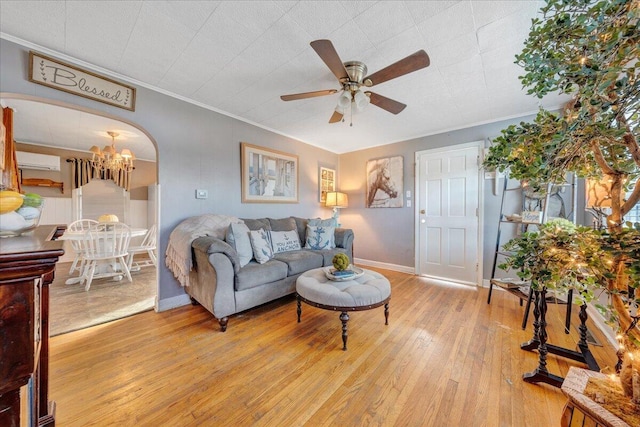 living room with ceiling fan with notable chandelier, light hardwood / wood-style flooring, a wall mounted AC, and crown molding