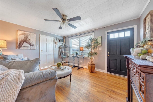 living room featuring ceiling fan, light wood-type flooring, and crown molding