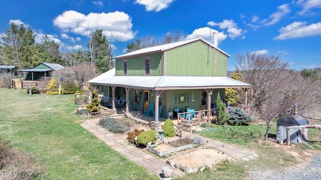 rear view of property featuring a porch, a chimney, and a yard