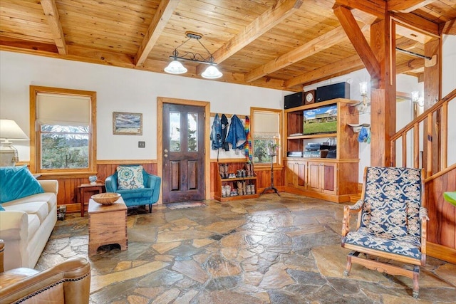 living area featuring beam ceiling, stone flooring, wainscoting, and wood ceiling