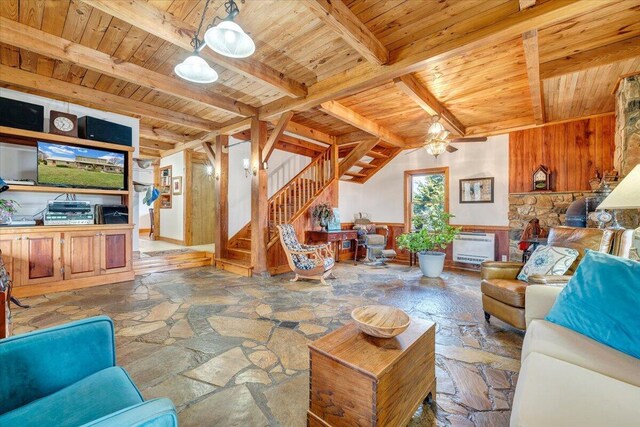 living room with stone flooring, wooden ceiling, beamed ceiling, stairway, and wood walls