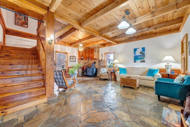 living room with a wood stove, stone flooring, stairway, wooden ceiling, and beam ceiling