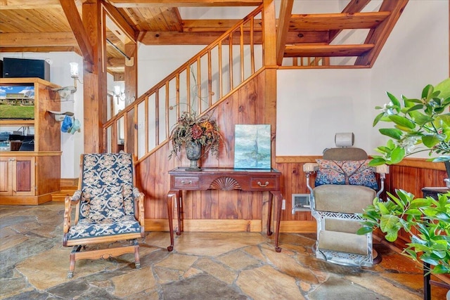 interior space featuring wooden walls, a wainscoted wall, stone floors, stairs, and wood ceiling