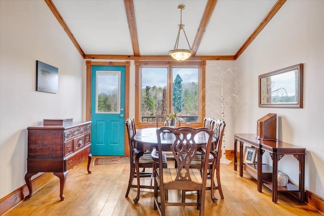 dining space with ornamental molding, light wood finished floors, and beamed ceiling