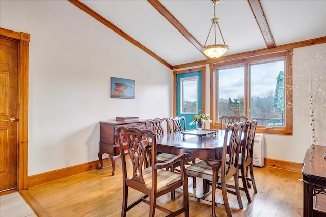 dining area featuring baseboards, light wood-type flooring, and vaulted ceiling with beams