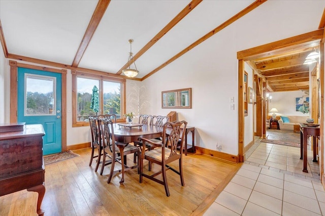 dining room featuring light wood-style floors, lofted ceiling with beams, and baseboards