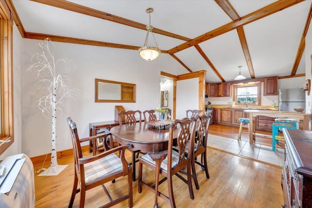 dining space with vaulted ceiling with beams and light hardwood / wood-style floors