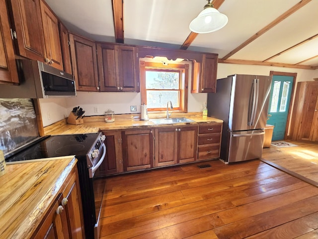 kitchen featuring a sink, appliances with stainless steel finishes, plenty of natural light, and dark wood finished floors