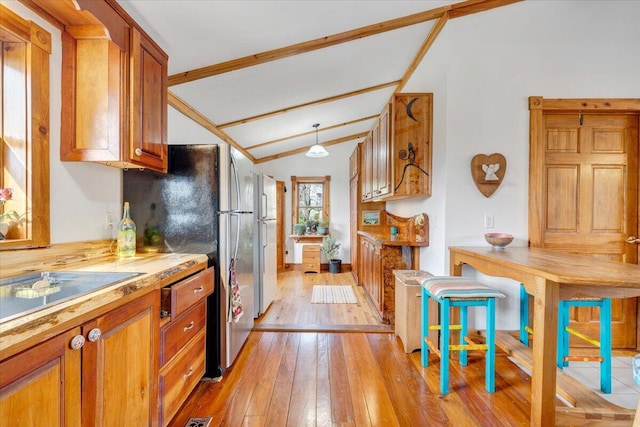 kitchen with lofted ceiling with beams, light wood-type flooring, and stainless steel refrigerator