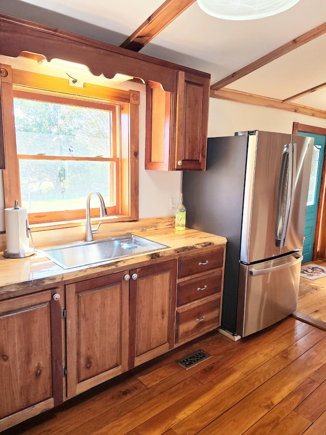 kitchen featuring freestanding refrigerator, visible vents, dark wood-style flooring, a sink, and brown cabinets