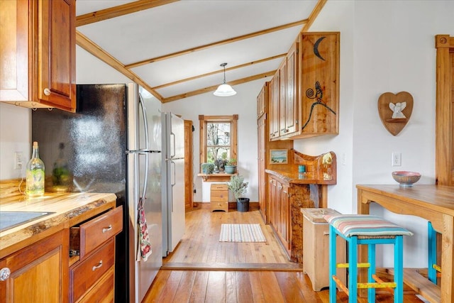 kitchen with lofted ceiling with beams, white refrigerator, decorative light fixtures, and light hardwood / wood-style flooring