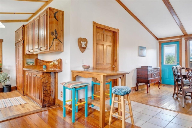 dining room featuring beam ceiling, high vaulted ceiling, and light hardwood / wood-style floors