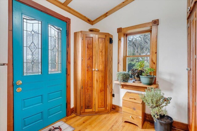 entrance foyer featuring crown molding, baseboards, and light wood finished floors
