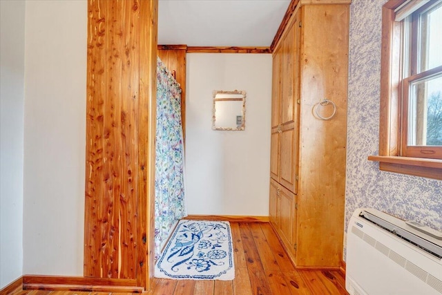 bathroom with a wall mounted AC, a healthy amount of sunlight, and hardwood / wood-style flooring