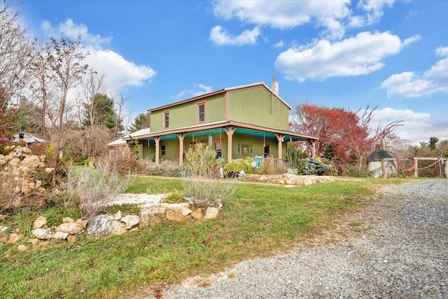 view of front of home featuring a porch, a chimney, and a front lawn