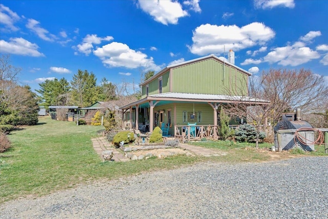 view of front of house featuring a front yard, an outbuilding, covered porch, and a chimney