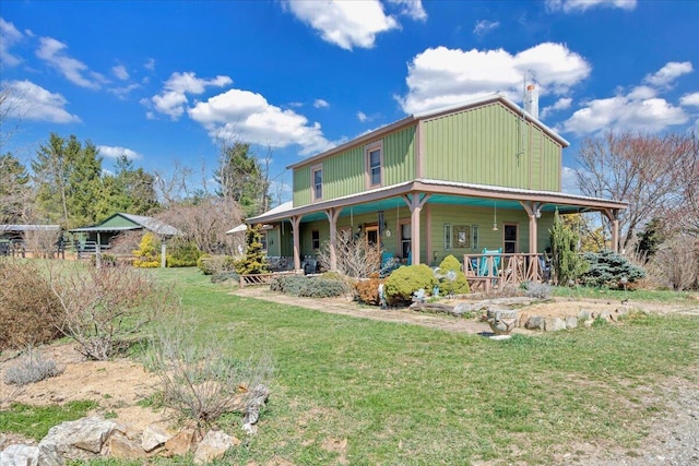 rear view of property featuring a chimney, covered porch, and a lawn