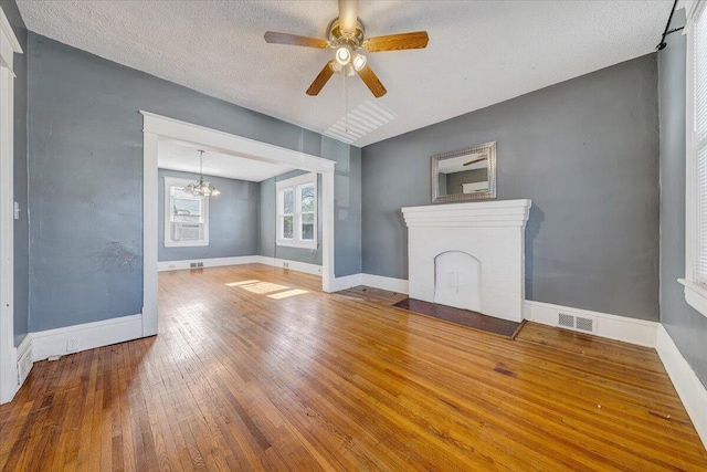 unfurnished living room with ceiling fan with notable chandelier, hardwood / wood-style floors, and a textured ceiling