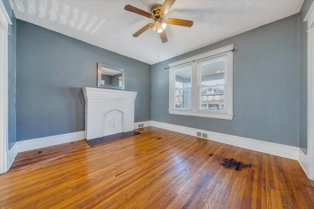 unfurnished living room with a fireplace, a textured ceiling, hardwood / wood-style flooring, and ceiling fan