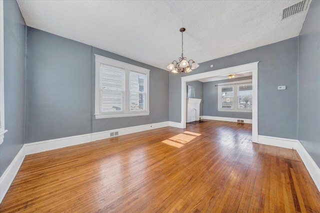 unfurnished dining area with hardwood / wood-style floors, a textured ceiling, and an inviting chandelier