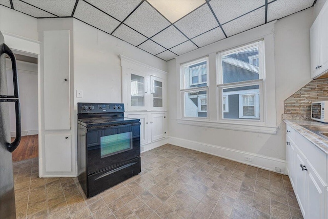 kitchen with a drop ceiling, white cabinets, and black appliances