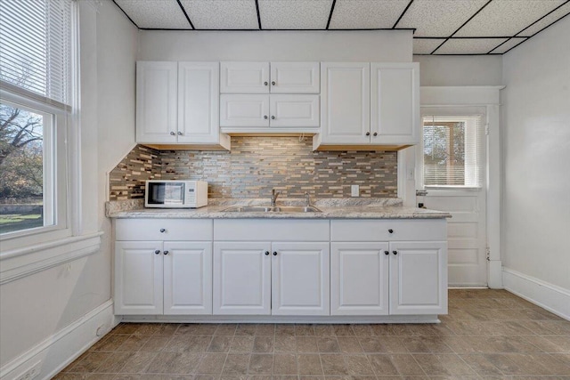 kitchen featuring tasteful backsplash, a drop ceiling, a healthy amount of sunlight, and sink