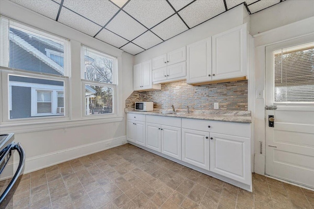 kitchen featuring backsplash, a paneled ceiling, stainless steel range, sink, and white cabinets