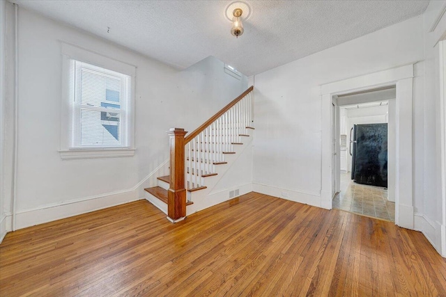 staircase featuring hardwood / wood-style floors and a textured ceiling