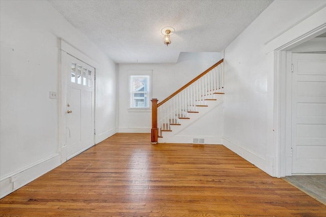 foyer entrance with hardwood / wood-style floors and a textured ceiling