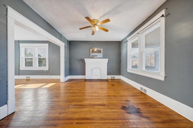 unfurnished living room featuring wood-type flooring, a textured ceiling, and ceiling fan