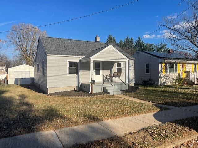 view of front of home with a garage, an outdoor structure, and a front yard