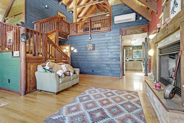 living room featuring high vaulted ceiling, wood walls, a wall unit AC, beam ceiling, and light hardwood / wood-style flooring