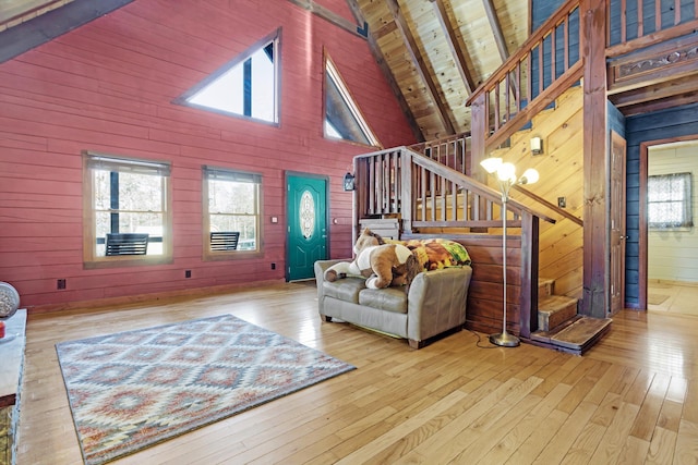 living room featuring wood walls, high vaulted ceiling, wooden ceiling, light wood-type flooring, and beamed ceiling