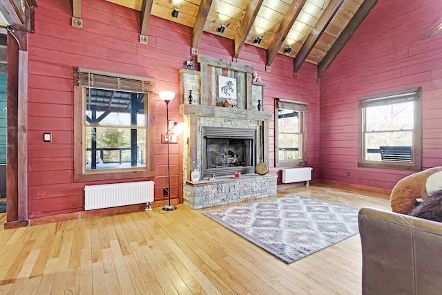 living room with radiator heating unit, wooden walls, wood ceiling, light hardwood / wood-style floors, and beam ceiling