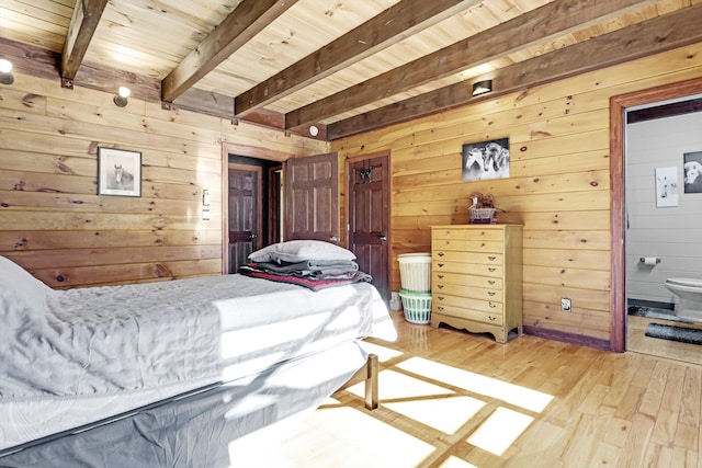 bedroom featuring wood ceiling, connected bathroom, beam ceiling, and wood walls