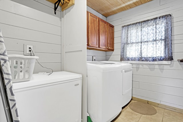 washroom featuring cabinets, washing machine and clothes dryer, and wood walls