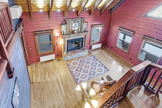 living room with a fireplace, wood walls, beam ceiling, wood ceiling, and light wood-type flooring