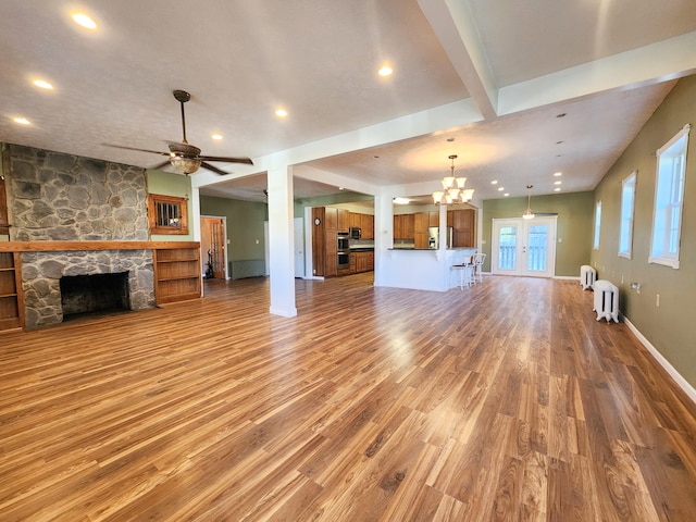 unfurnished living room featuring a fireplace, hardwood / wood-style floors, ceiling fan with notable chandelier, and beam ceiling