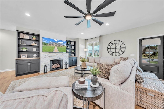 living room with a fireplace, light hardwood / wood-style flooring, a wealth of natural light, and ceiling fan