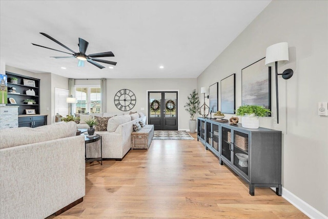 living room with french doors, light wood-type flooring, and ceiling fan