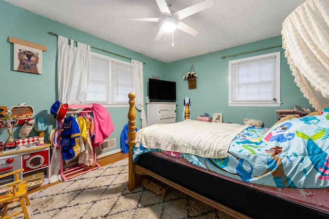 bedroom featuring ceiling fan, multiple windows, and light wood-type flooring