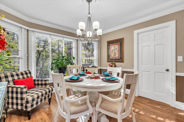 dining room with hardwood / wood-style flooring, ornamental molding, and an inviting chandelier