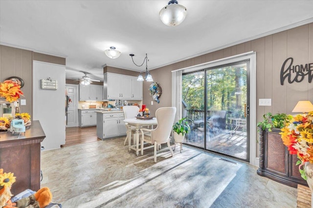 kitchen featuring white cabinetry, ceiling fan, hanging light fixtures, a breakfast bar, and a kitchen island