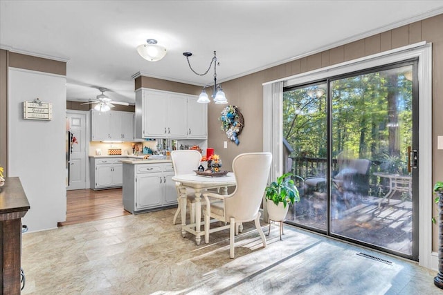 kitchen featuring ornamental molding, ceiling fan with notable chandelier, light hardwood / wood-style flooring, white cabinetry, and hanging light fixtures