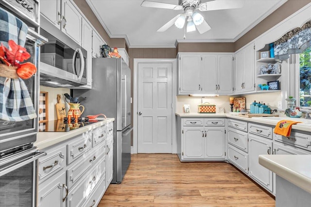 kitchen with white cabinets, crown molding, ceiling fan, light wood-type flooring, and stainless steel appliances