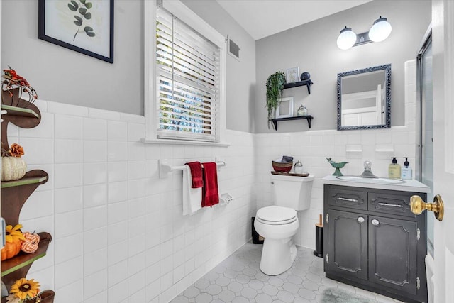 bathroom with tile patterned floors, vanity, toilet, and tile walls