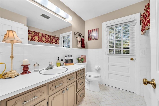 bathroom featuring vanity, toilet, and tile walls